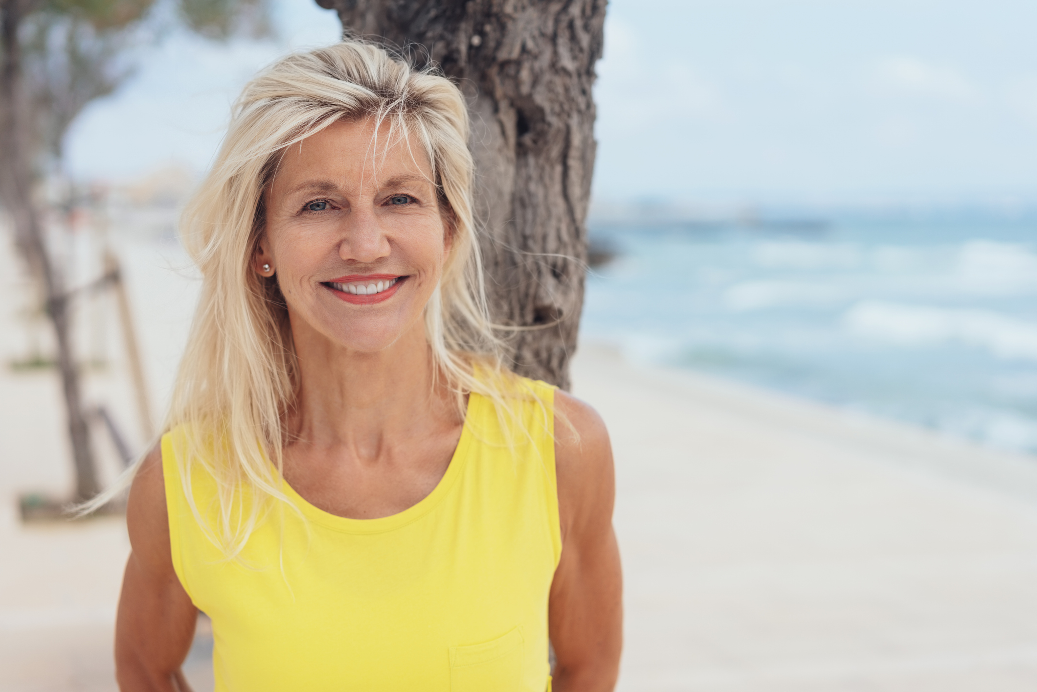 Attractive tanned blond woman standing on a beach
